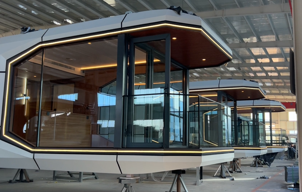 Row of futuristic bahria homes House modular units under construction, featuring large glass panels, LED lighting, and sleek geometric design for modern smart living.