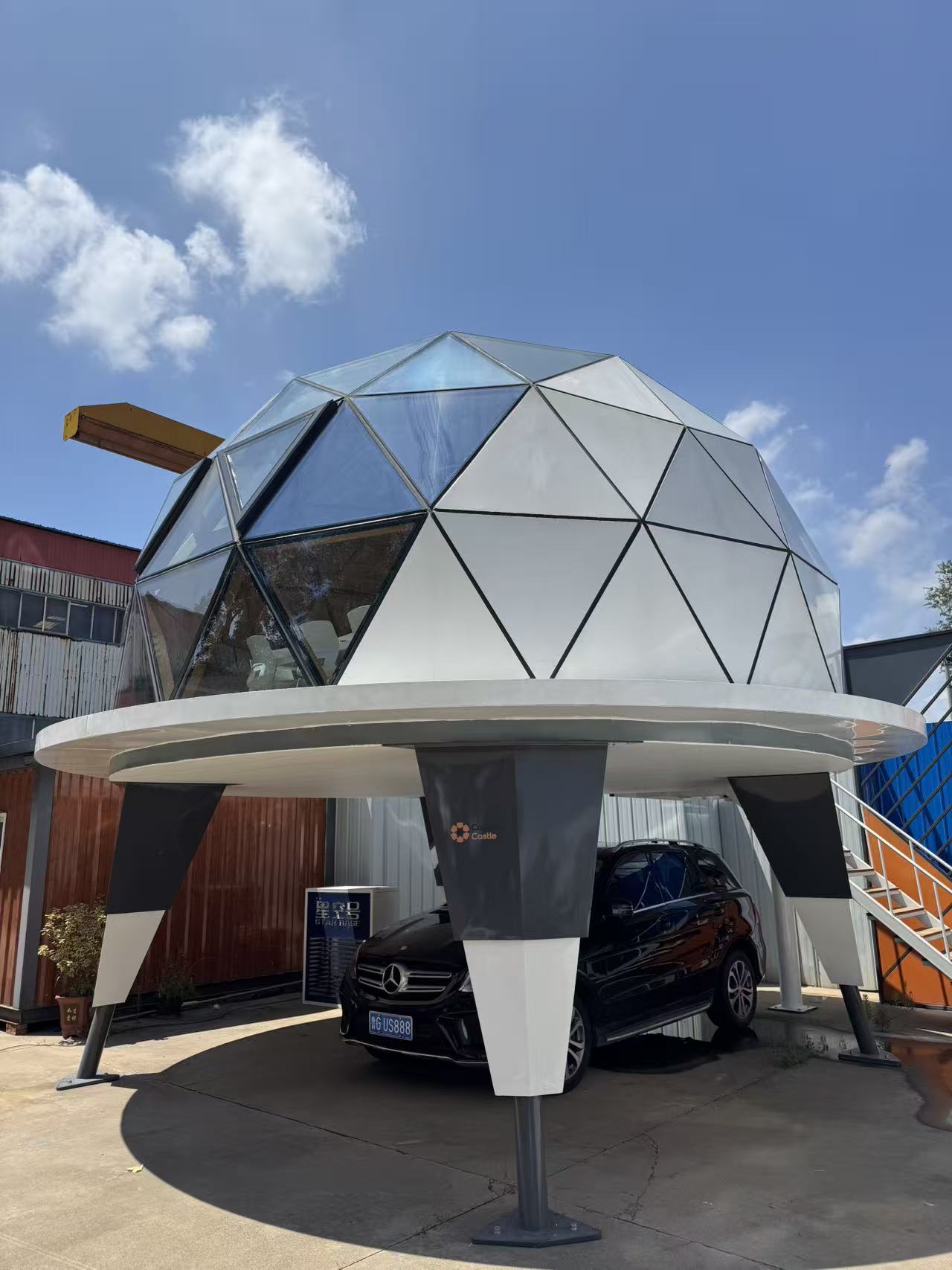 bahria homes House C7 Plus elevated geodesic dome pod with glass panels and futuristic framework, featuring a car parked underneath against a bright blue sky.