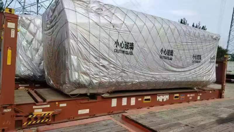 bahria homes House unit securely packaged with protective wrapping labeled “Caution Glass,” loaded on a shipping container platform for safe international transport.